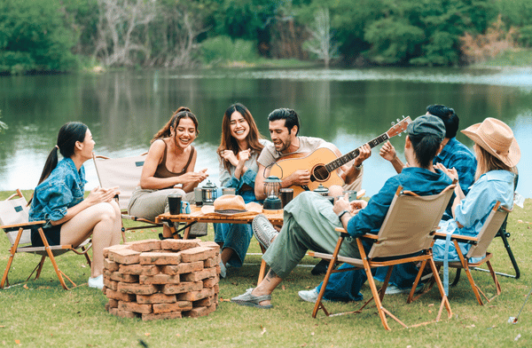 Amis assis autour d’un feu de camp au bord du lac – Accéder aux playlists Spotify pour les vacances d’été
