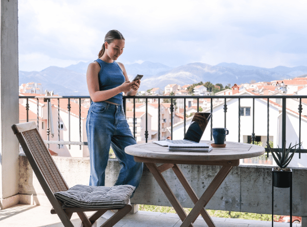 Femme avec ordinateur portable sur une terrasse avec vue – Réservez votre logement pour une workation